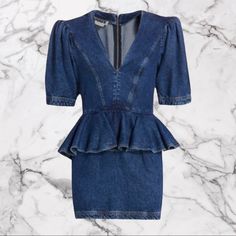 a blue denim dress with ruffles on the front and back, against a marble background