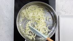 someone is cooking pasta in a pan on the stove top with a spatula next to it