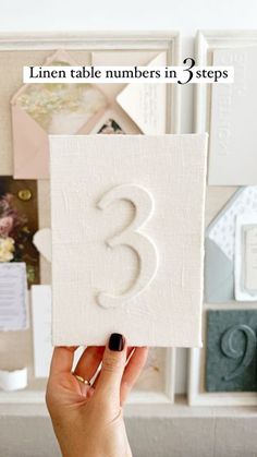 a person holding up a card with the number three on it in front of a desk