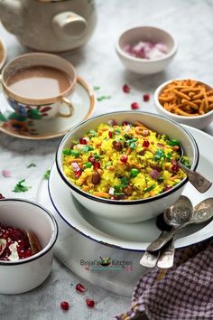 there is a bowl of food on the table with other bowls and spoons next to it