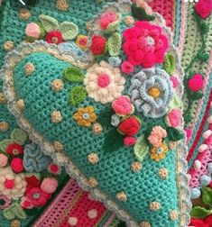 two crocheted pillows on top of each other in different colors and sizes with flowers