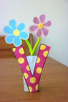 a vase with flowers in it sitting on a table next to a card and paper