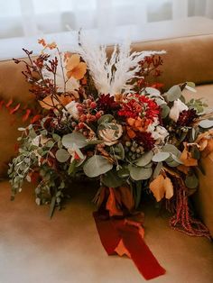 an arrangement of flowers and foliage on a couch