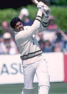 a man swinging a bat at a ball during a cricket game in front of a crowd