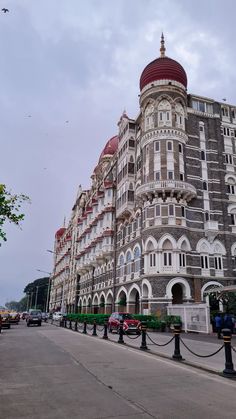 a large building with many windows and balconies on the top floor, next to a street