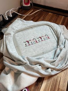 a laptop computer sitting on top of a wooden floor next to a pile of blankets