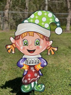 a yard decoration featuring a girl with a green hat and red dress, standing in the grass