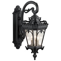 an old fashioned wall light with glass panels and ornate carvings on the front, in black