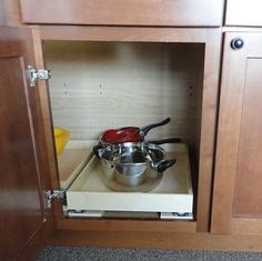 an open cabinet with pots and pans in it