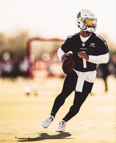 a football player is running with the ball in his hand and wearing a helmet on