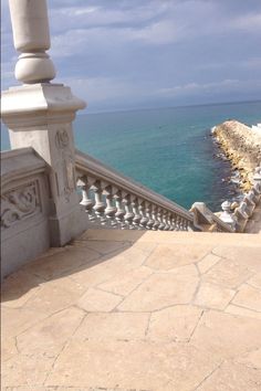 a bench sitting on top of a stone walkway next to the ocean