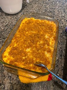 a casserole dish is sitting on the counter next to a cup and spoon