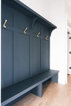 an empty bench in the middle of a room with several coat hooks on it's back