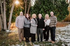 a group of people standing next to each other in front of some snow covered trees