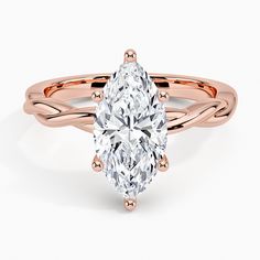 a rose gold ring with a pear shaped diamond in the center and an intricate band around it