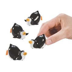 three small black and white penguin figurines being held by a hand