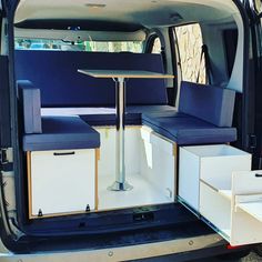 the back end of a van with two tables and stools