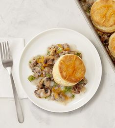 a white plate topped with food next to a pan filled with meat and cheese pies