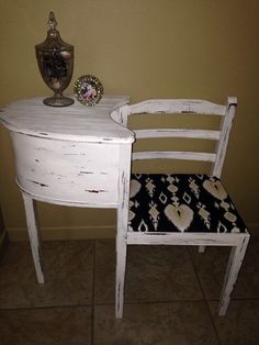 a white desk with a chair next to it and a vase sitting on top of it