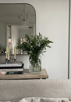 a vase filled with flowers sitting on top of a bed next to a mirror and books