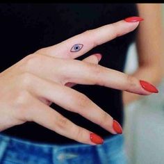 a woman's hand with an evil eye tattoo on her left thumb and finger