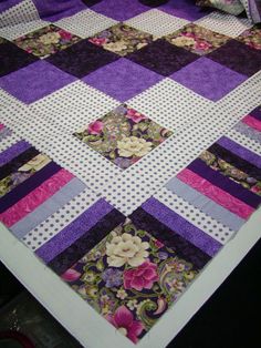 a quilted table top with purple and white flowers on it, sitting on a black surface