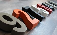 four different colored letters sitting on top of a hard wood floor next to each other