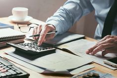 a man is using a calculator and pen to check the numbers on his desk