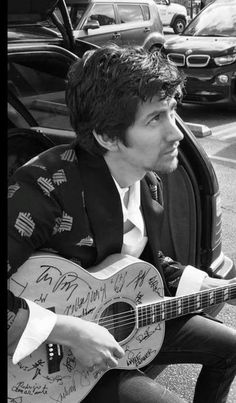 a man sitting on the ground with a guitar in his hand and autographed