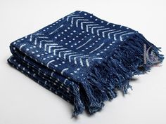 a blue and white patterned blanket with fringes on the ends, sitting on top of a table