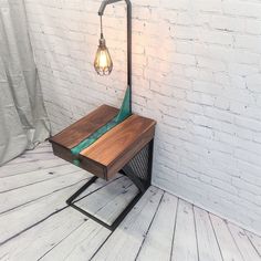 a wooden table with a lamp on top of it next to a white brick wall