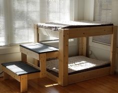 a wooden bunk bed sitting next to a window on top of a hard wood floor