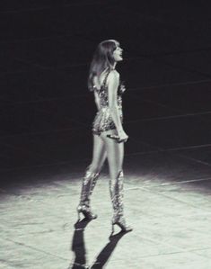 a black and white photo of a woman in high heeled boots standing on a stage