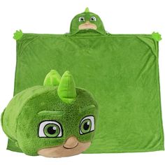 a green stuffed animal sitting next to a green blanket with an angry bird on it's head