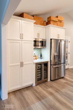 a kitchen with white cabinets and stainless steel refrigerator freezer combo in the center, along with hardwood flooring