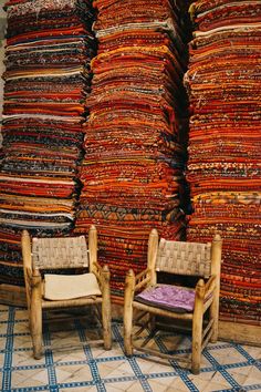 two chairs sitting next to each other in front of stacks of fabrics