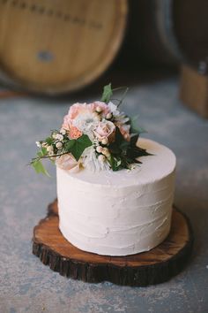 a white cake with flowers on top is sitting on a wooden stand and has an instagram post about it