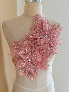 a mannequin with pink flowers on it's chest and two silver pins in the back