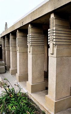 the building is made of concrete and has many pillars on each side with decorative designs