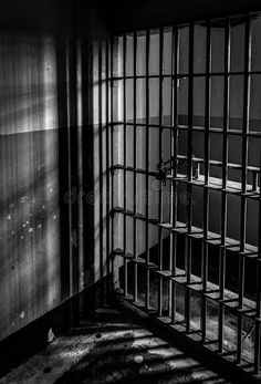 an empty jail cell with bars on the wall and shadows cast on the walls behind it