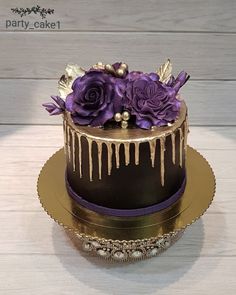 a chocolate cake with purple flowers and icing drizzled on the top