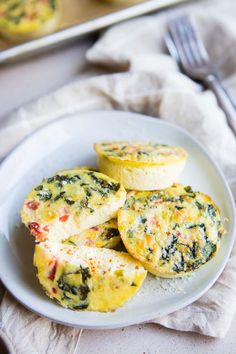 small muffins with spinach and cheese on a plate next to a fork