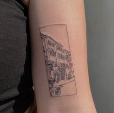 a woman's arm with a small black and white cityscape tattoo on it