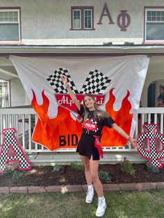 a woman standing in front of a flag with flames and checkered flags on it