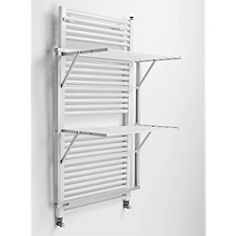 a white radiator mounted to the side of a wall next to two shelves