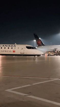 an air canada express jet parked on the tarmac at night with other planes in the background