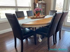 a dining room table with black chairs and a potted plant on top of it