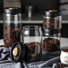 three glass jars filled with coffee beans on top of a table