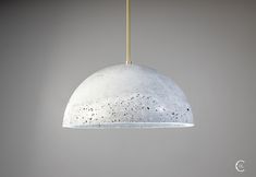 a white pendant light hanging from a gold colored ceiling fixture with speckled paint on it