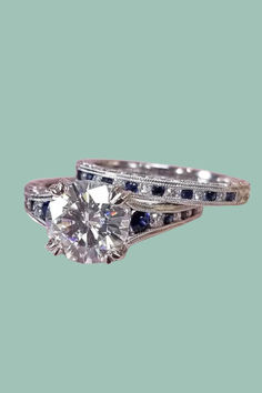 a diamond and blue sapphire engagement ring with matching band on a light green back ground